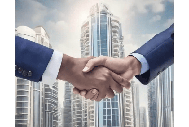 Close-up of two individuals in dark blue suit jackets exchanging a handshake in front of tall, modern architectural buildings under a partly cloudy sky.