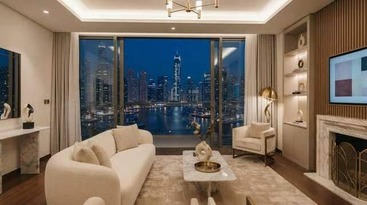 Luxurious cream-toned living room with marble fireplace and city skyline visible through floor-to-ceiling windows at night.